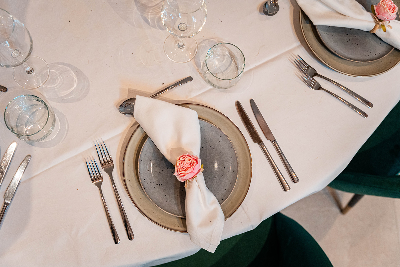 Detail van gedekt couvert met handgemaakt servies en roze roos