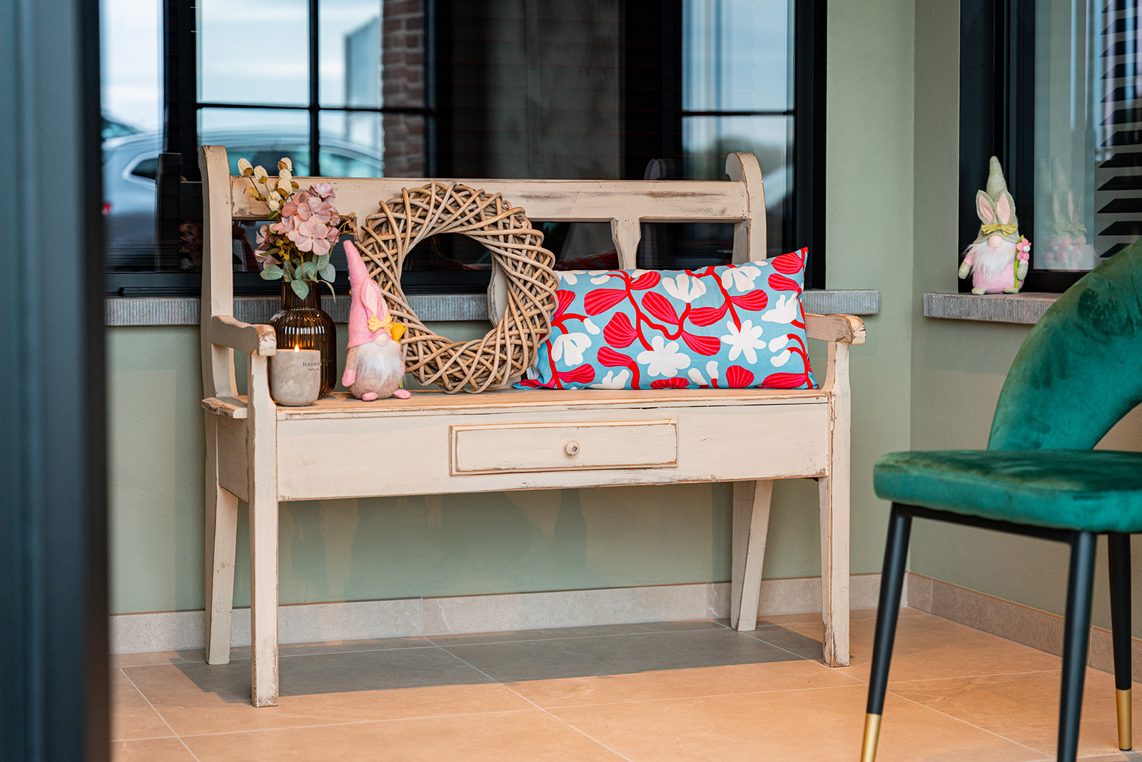 Sfeervolle inkomhoek met houten bank, krans en bloemen