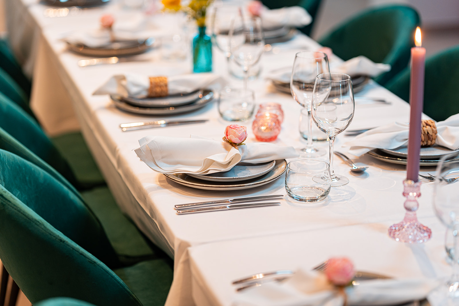 Detail van gedekte feesttafel met smaragdgroene velvet stoelen en roze kaars