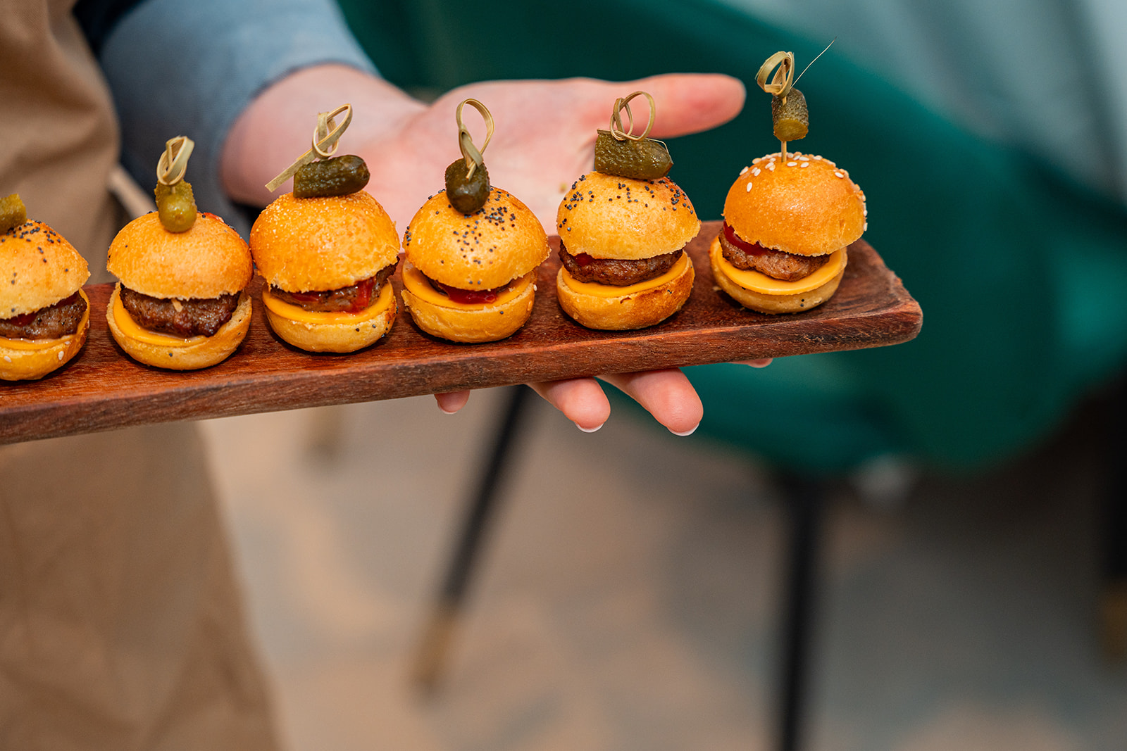 Mini cheeseburgers met augurk op een houten plank