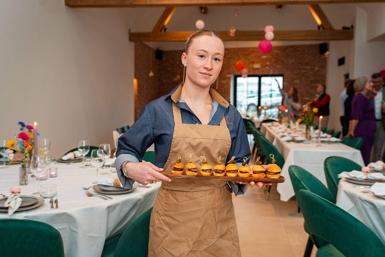 Delivento gastvrouw met plank vol mini hamburgers in de zaal