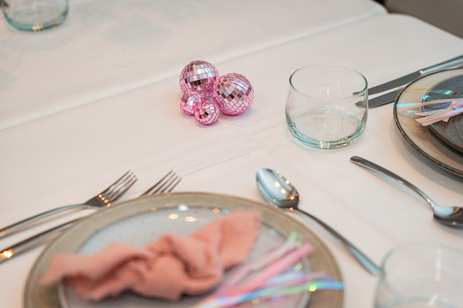Sfeervol gedekte tafel met roze discoballen en velvet stoel