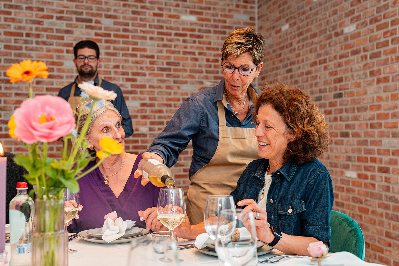 Delivento gastvrouw schenkt witte wijn in tijdens een gezellig diner
