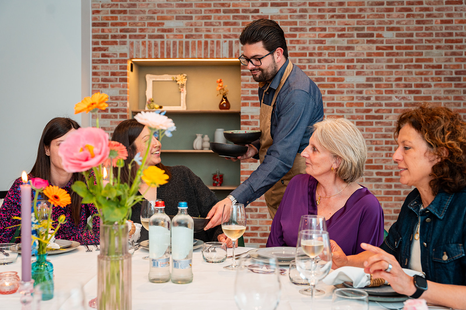 Delivento ober serveert voorgerecht aan tafel met gasten