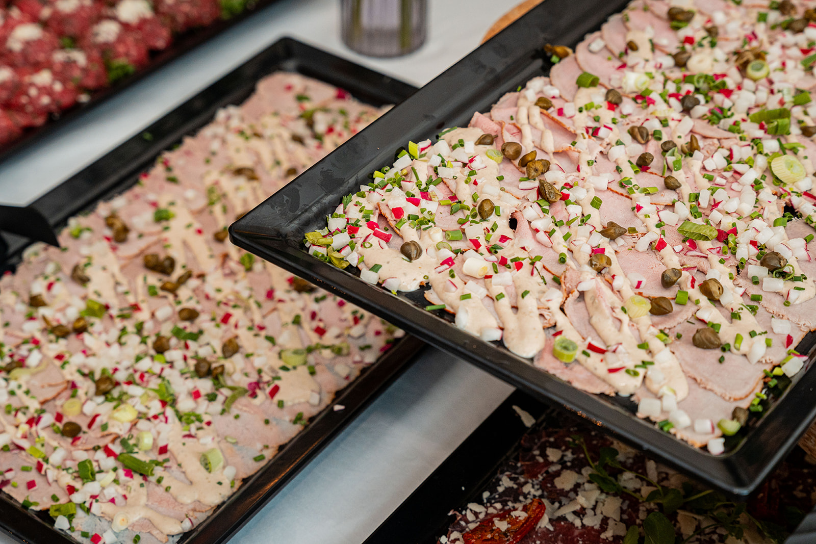 Schotels met gerookte ham, kappertjes, radijs en dressing op buffet