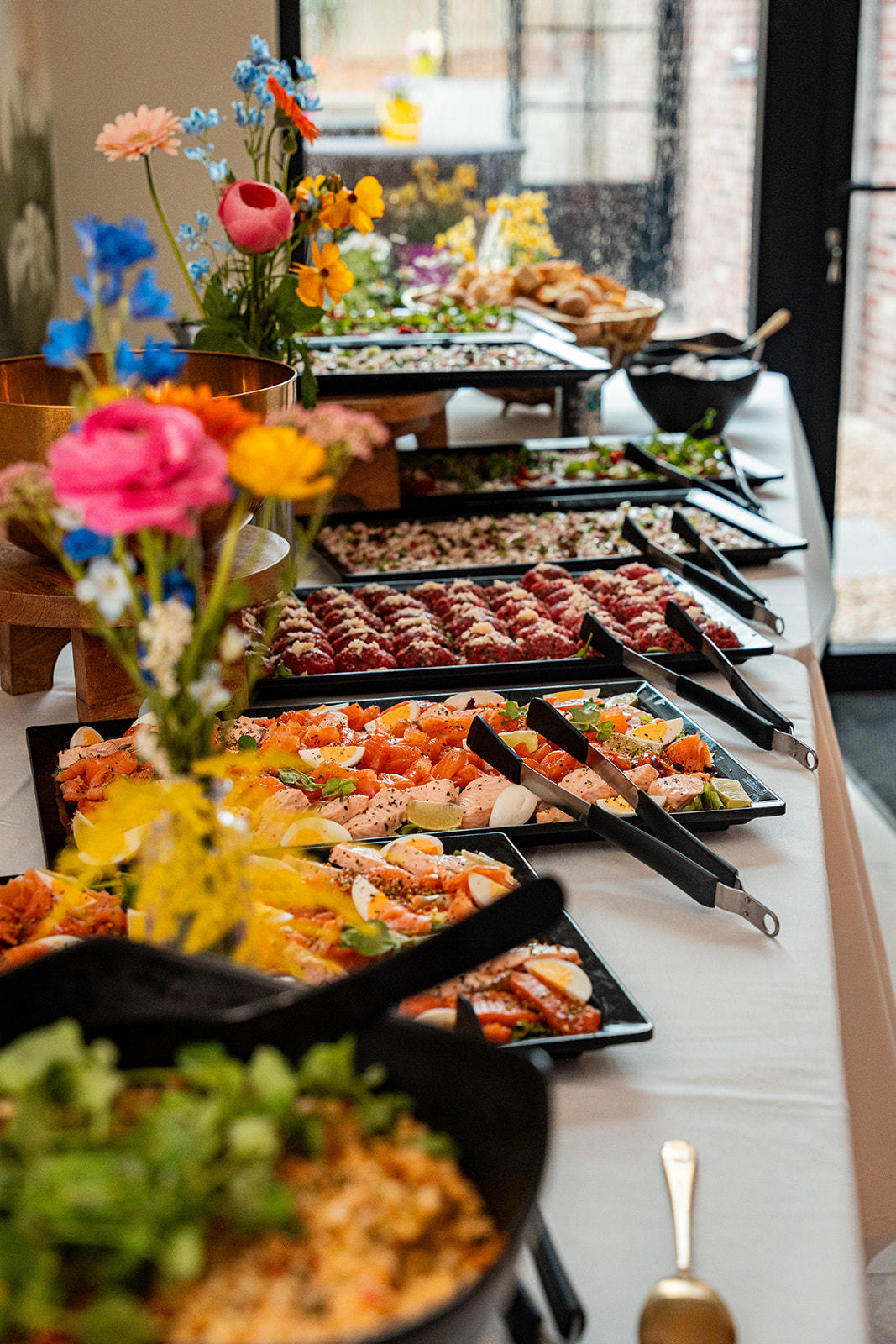 Uitgebreid buffet met visschotels, vleeswaren en kleurrijke bloemen