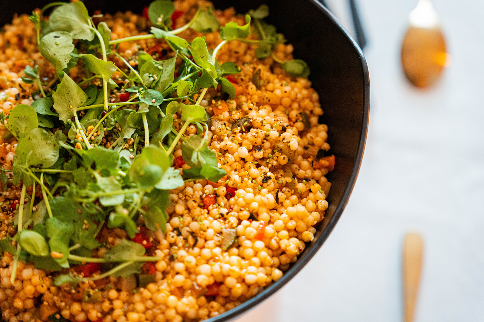 Parelcouscous met paprika en tuinkers in zwarte schaal