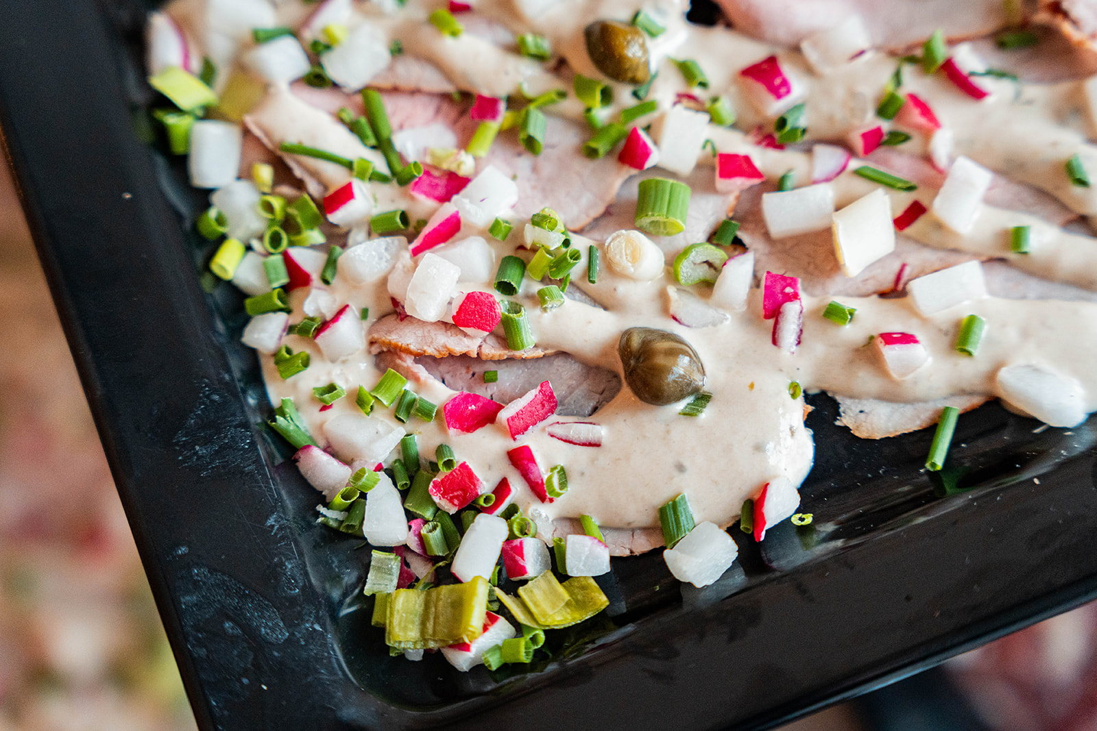 Detail van gerookte kalkoen met radijs, lente-ui en kappertjes in dressing
