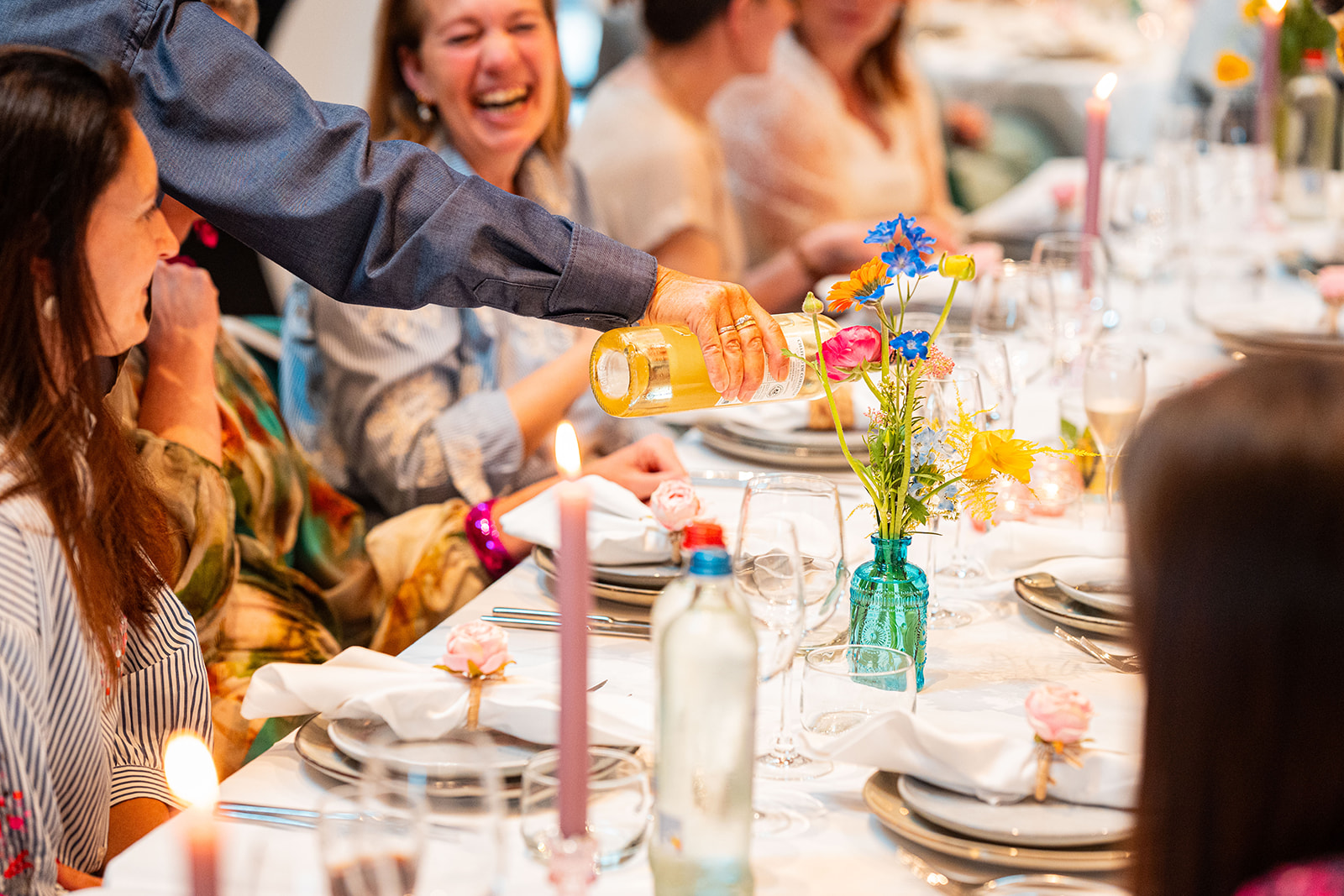 Delivento gastvrouw schenkt witte wijn in tijdens een sfeervol diner met kaarslicht
