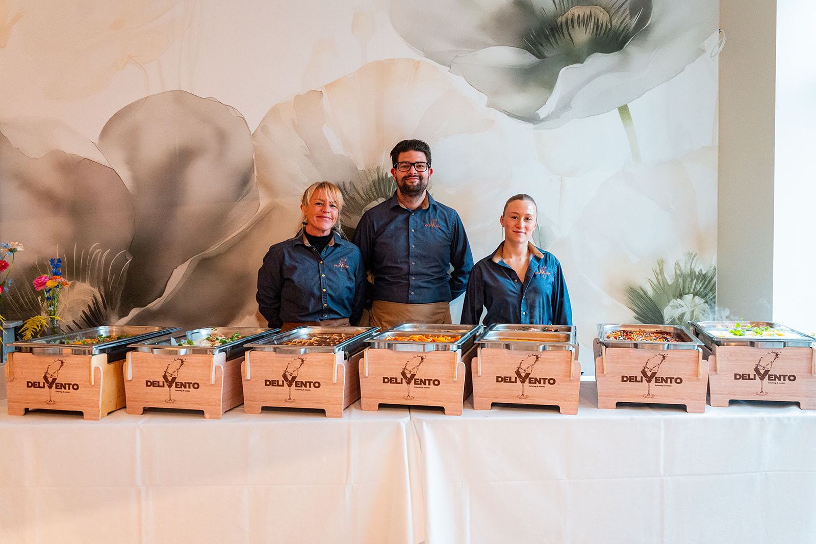 Delivento team poseert trots achter buffet met chafing dishes