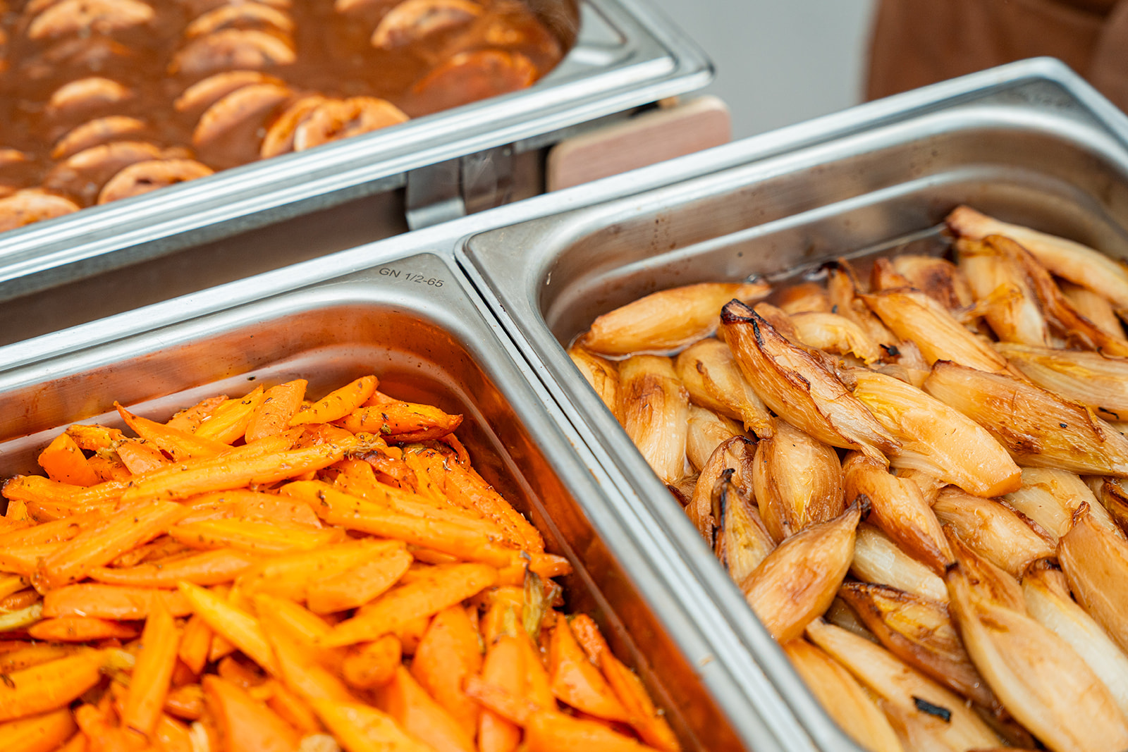 Detail van geglaceerde wortelen en gestoofd witloof in chafing dishes