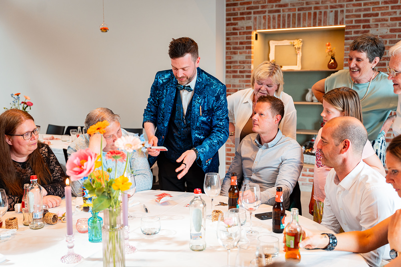 Goochelaar toont kaartentruc aan tafel vol verbaasde gasten