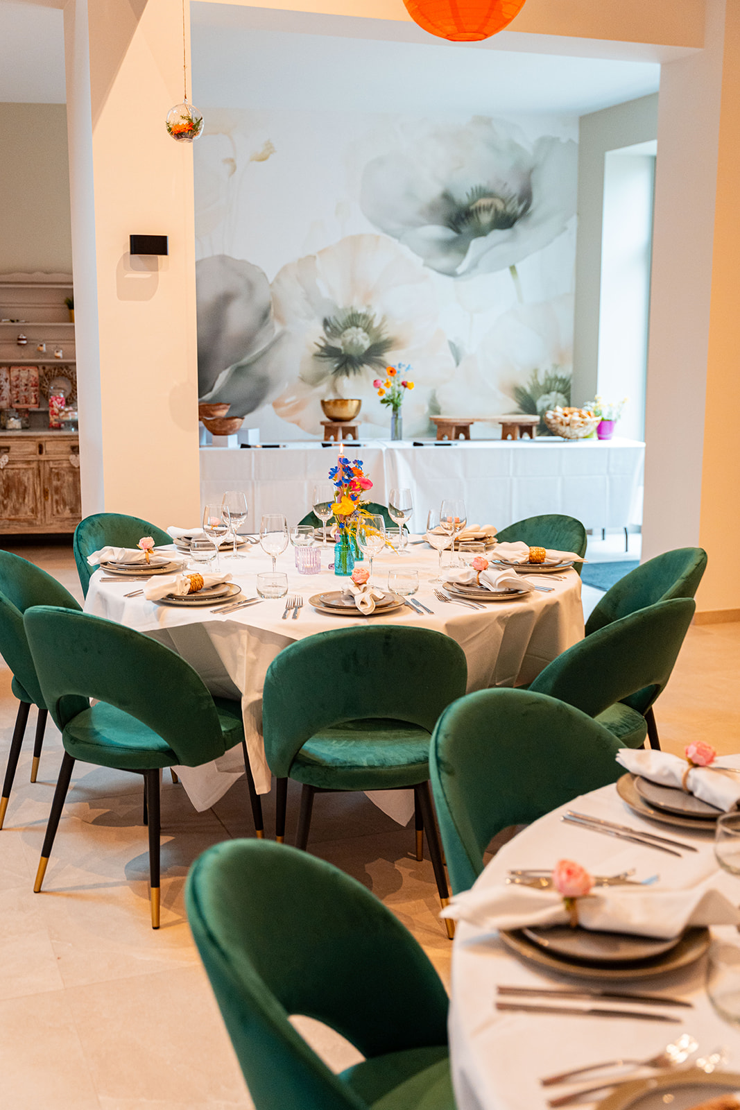 Ronde tafel met smaragdgroene stoelen voor sfeervolle bloemenwand
