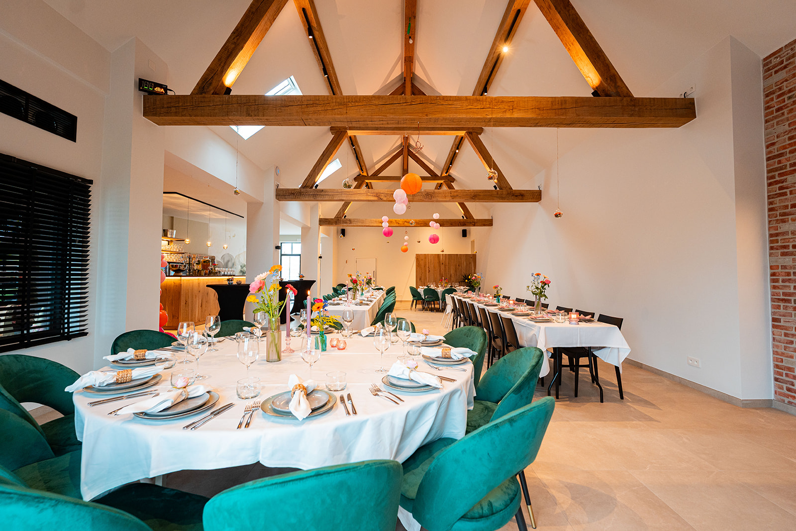Ronde tafel met smaragdgroene stoelen onder authentieke houten balken
