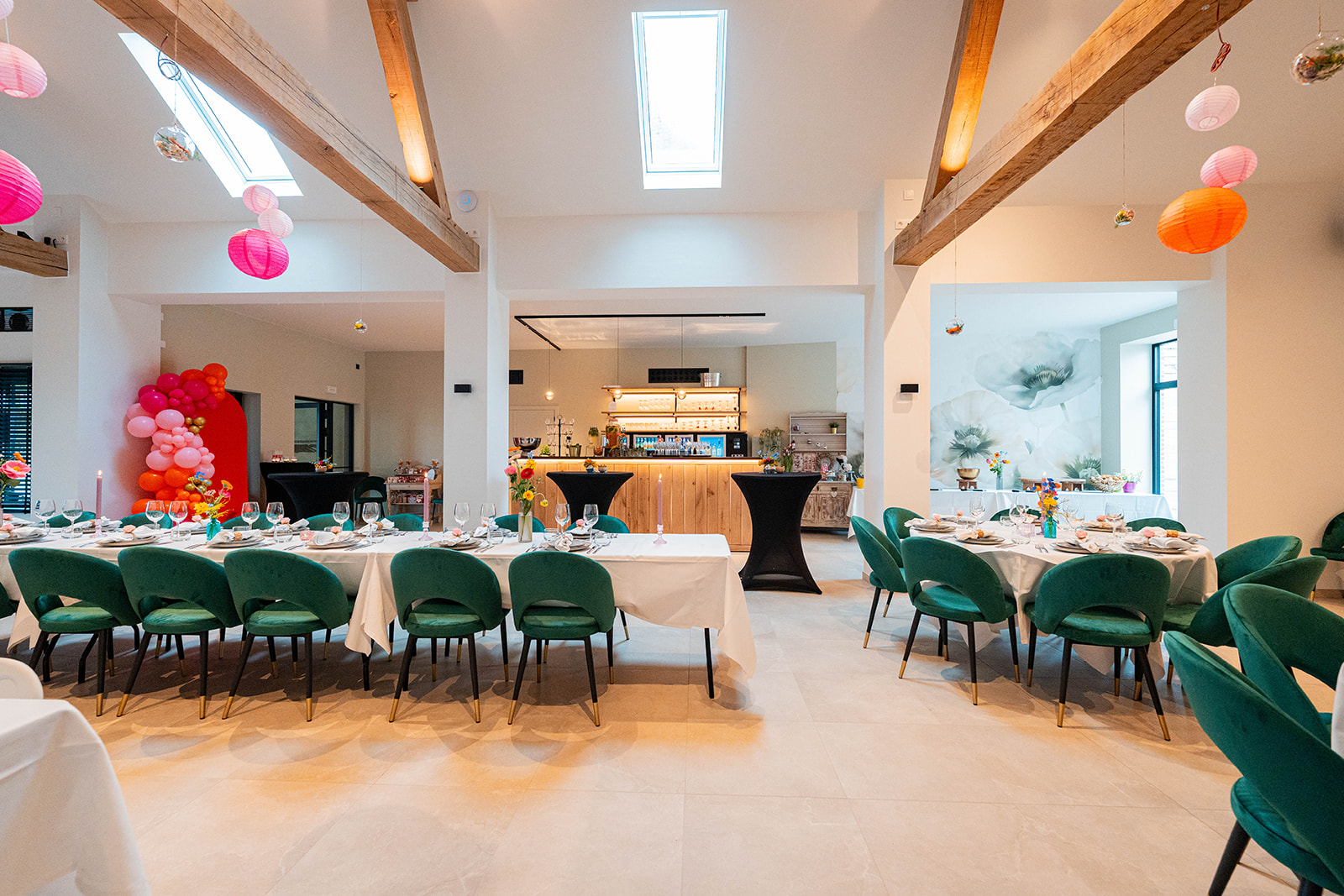 Lange feesttafels met smaragdgroene stoelen en daklicht