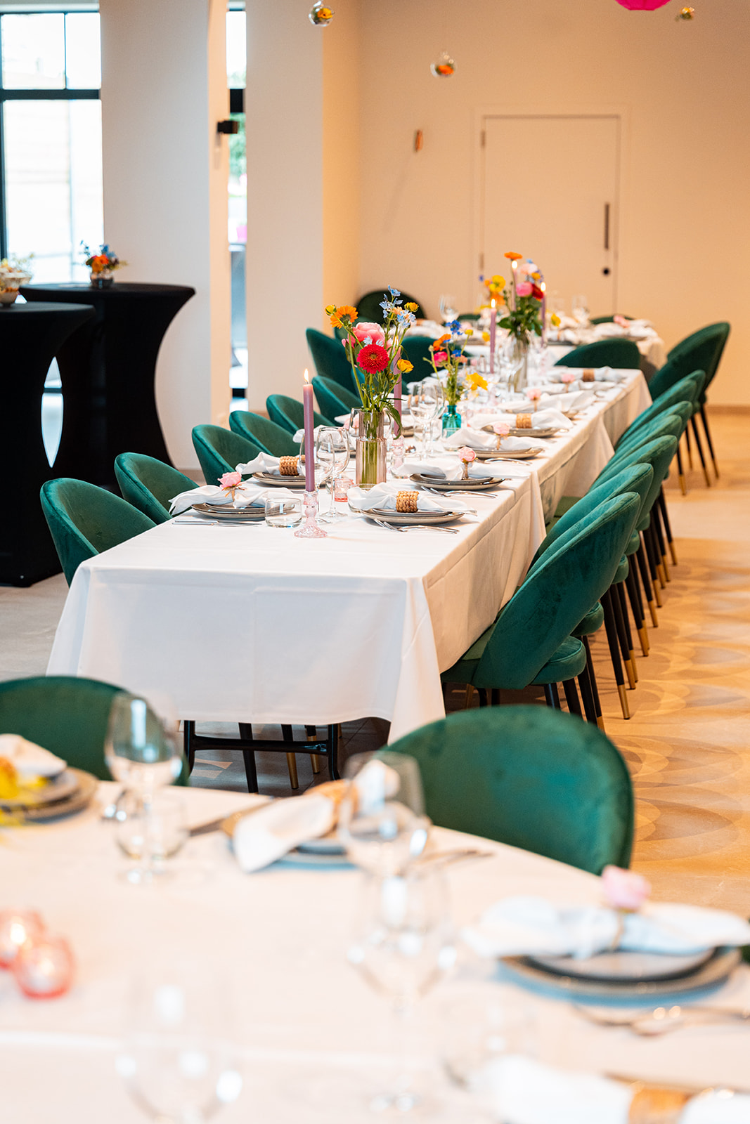 Gedekte feesttafel met smaragdgroene stoelen en bloemen