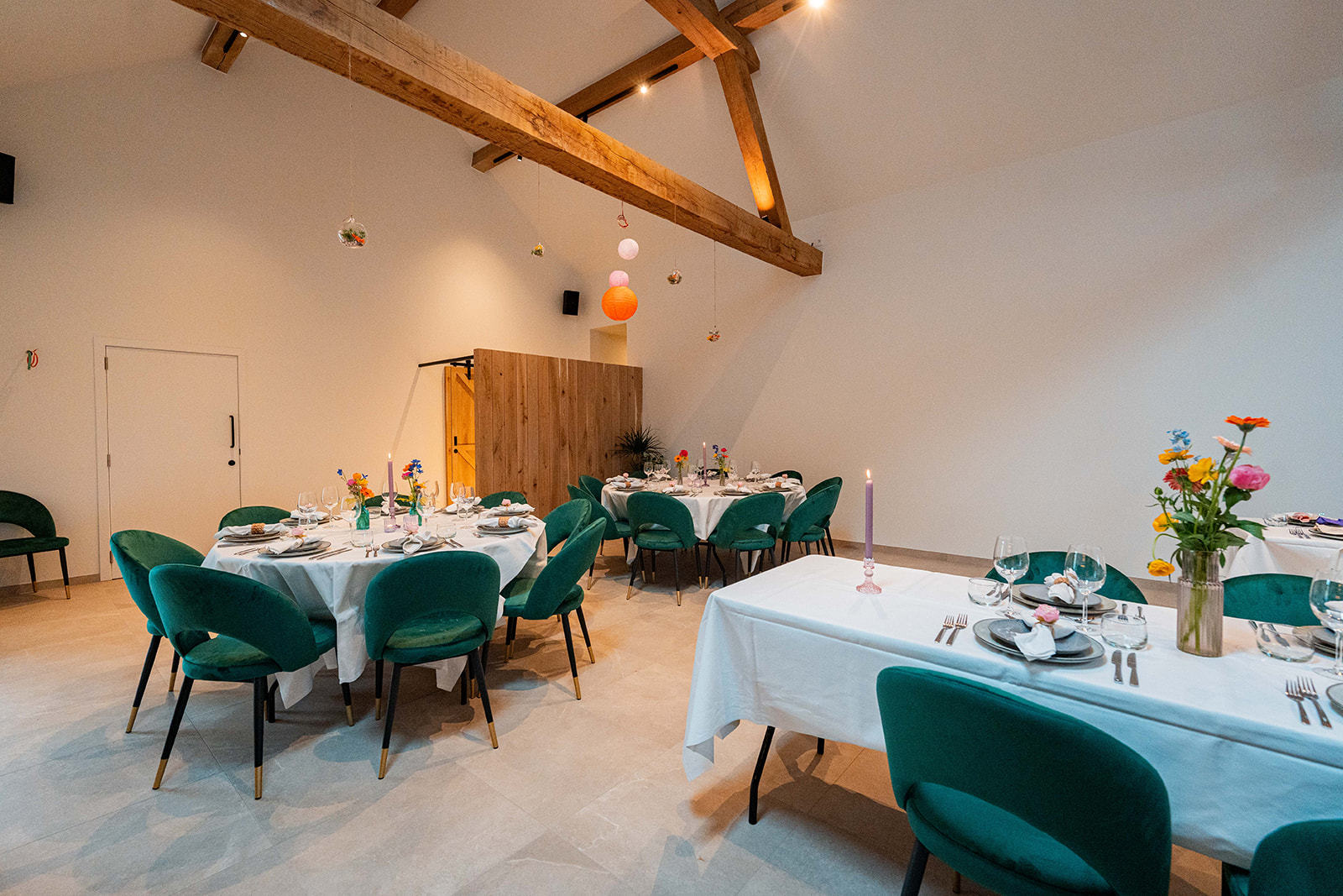 Volledig gedekte feestzaal met smaragdgroene stoelen onder authentieke houten balken